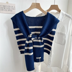 Détail d'un châle en laine à rayures noué sur une chemise avec étiquette de composition