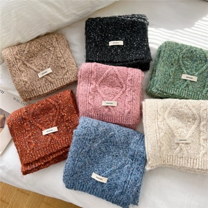 Folded chunky knit scarves in multiple colors with classic cable pattern on white background