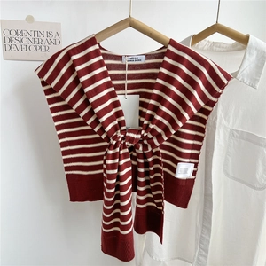 Vue détaillée d'un châle en tricot rayé rouge et blanc noué sur une chemise blanche