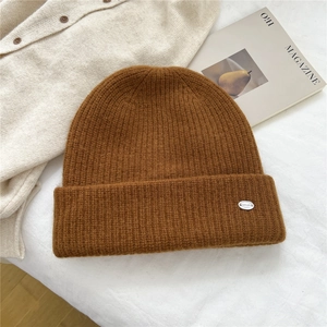 Close-up of caramel brown ribbed knit beanie with silver BOWLOW metal logo tag