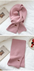 Close-up of pink knitted scarf featuring detailed rib-knit texture and brown leather tag