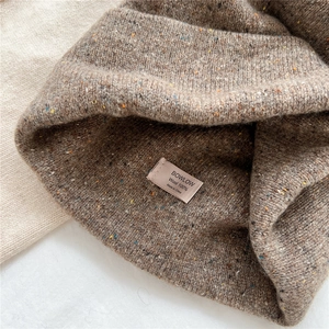 Detail of the 100% wool label inside the brown speckled knitted beanie hat for winter