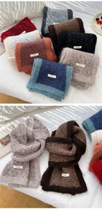 Detail view of thick two-tone knitted scarf with soft wool texture and brand label