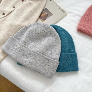 Chunky knit beanies in grey and blue with flecked texture on soft fabric background