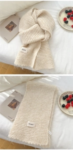 Detail of soft cream knitted scarf with fringe edge and Bonogeed brand woven label
