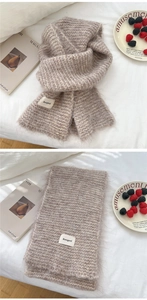 Detail of oat-colored knitted scarf showing fluffy mohair texture and brand label