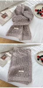 Close-up of thick knit winter scarf showing plush texture and brand label detail
