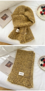 Detail of ginger yellow knit scarf showing thick ribbed texture and brand label