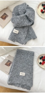 Detail of grey knitted scarf showing soft mohair texture and branded woven label