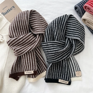 Striped knit scarf in coffee and black tones with brand label on a cozy white background