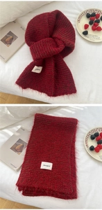 Detail of burgundy knit scarf with soft fluffy texture and minimalist brand label