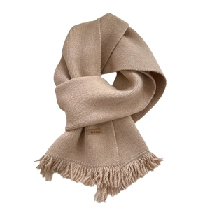 Solid beige knitted winter scarf with fringe tassels and handmade leather label detail