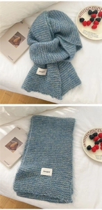 Close-up of blue and green bicolor knit scarf featuring a soft fuzzy texture and brand label