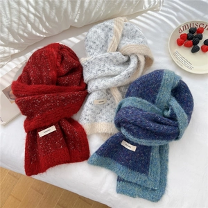Winter knitted scarves in red, grey, and teal colors shown in a cozy home setting