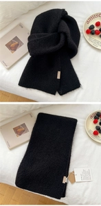 Detail of black knitted scarf with fluffy texture, textile label and brand tags