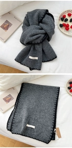 Close-up of thick dark grey knitted scarf with black stitching and white woven label