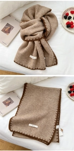 Detail of knitted winter scarf in camel brown with dark coffee lockstitch edges and logo
