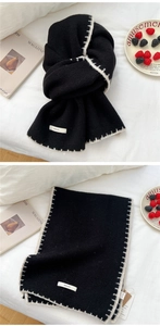 Detail of black knitted scarf featuring white blanket stitch edges and BOWLOW woven label