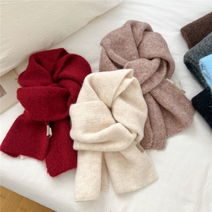 Thick knitted winter scarves in multiple colors displayed on white bedding for a cozy look