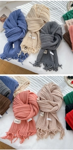 Close-up of thick knitted scarves with fringe detail in multiple trendy colors