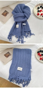 Detail of blue chunky knit scarf with ribbed texture and handmade tassel decorative fringe
