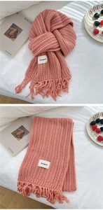 Detail of pink knitted scarf with fringe tassels and minimalist brand woven label