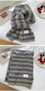 Detail of purple and green striped knit scarf with soft mohair texture and logo tag