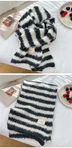 Close-up of fuzzy black and white striped knit scarf with minimalist ins brand label