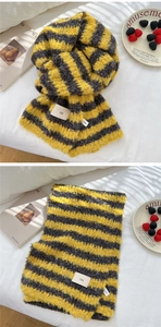 Detailed knit texture of a yellow and grey striped winter scarf with an ins woven label