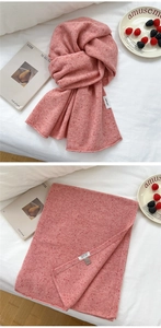Detail of coral pink wool scarf featuring 100% wool label and soft knitted texture