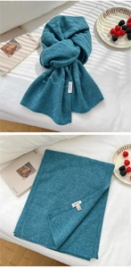 Detailed view of knitted wool scarf texture with composition label and branding tag