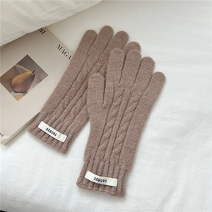 Detalle de guantes de punto trenzado café con textura de lana y etiqueta de marca tejida