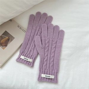 Detalle de guantes de punto trenzado morados con puños acanalados y etiqueta
