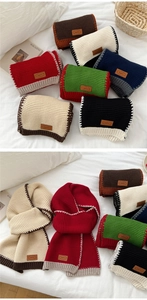 Close-up of chunky knit scarves with contrast stitching and leather brand tags