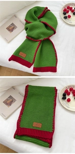 Detailed knit texture of red and green contrast wool scarf with leather brand tag