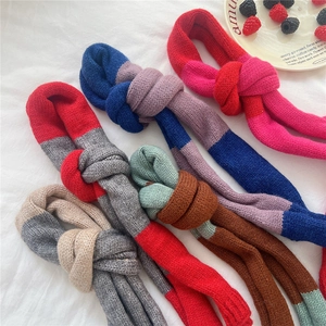 Macro detail of various color-blocked chunky knit scarves in soft wool texture for winter