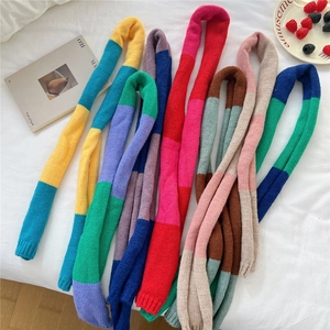 Colorful knit scarf in vibrant contrast colors flat lay on white linen for winter style