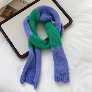 Detailed knit texture of purple and green color-block scarf with ribbed edges on a tray