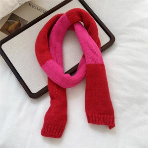Detail of red and pink contrast knit scarf showing thick wool texture and ribbed edges