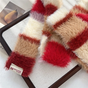 Detail of colorful plush scarf with soft texture and brand label in a wooden tray
