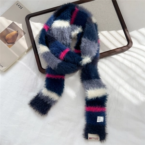 Close-up of colorful striped plush scarf with luxury brand label on a wooden tray