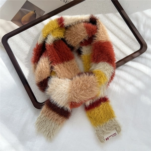 Close-up of plush striped scarf texture showing the woven brand tag in a wooden tray