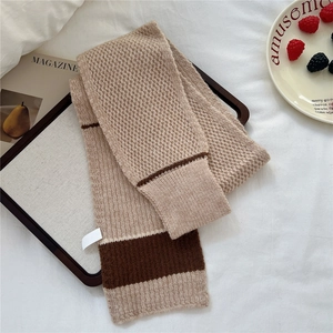 Detailed knit texture of a two-tone striped scarf on a cozy lifestyle display