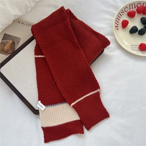 Detail of red knit scarf with wavy pattern and stripes on textured white background
