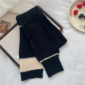 Detail of striped knitted scarf with black, cream and grey color block textures