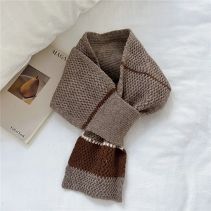 Detail of striped knitted cross scarf in brown and beige with thick woven texture