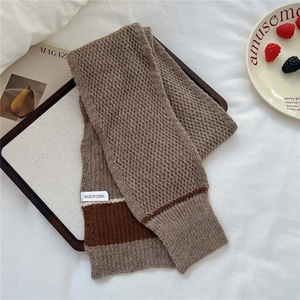 Detail of chunky wave-knit scarf texture with two-tone stripes and fabric label