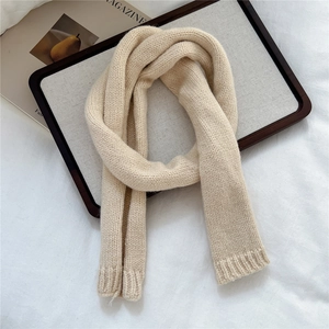 Close-up of beige thick knit scarf showing detailed ribbed texture and soft wool blend fabric