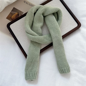 Detailed close-up of light green knit scarf showing soft ribbed edge texture and weaving