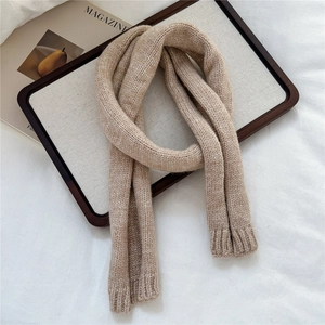 Close-up of beige chunky knit texture and ribbed hem detail on a winter scarf